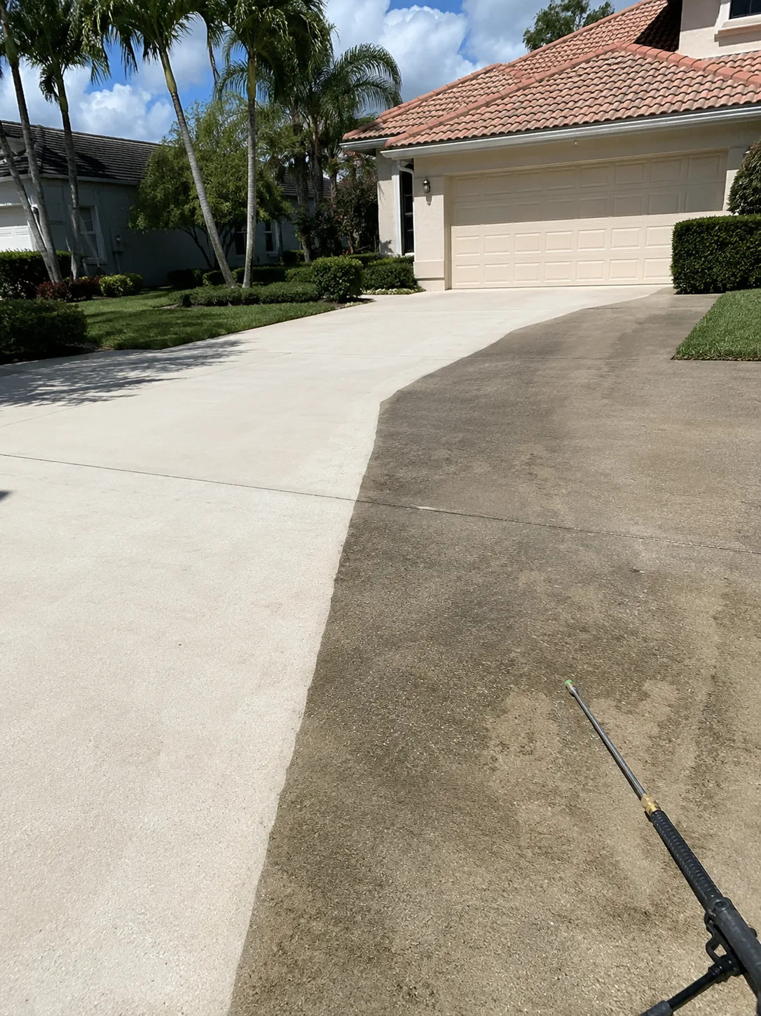 A driveway shown partly pressure washed, with the cleaned concrete beside the uncleaned surface